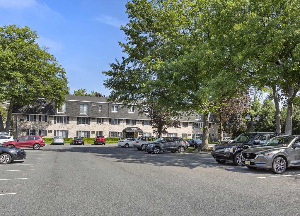 a parking lot with cars in front of a building with trees