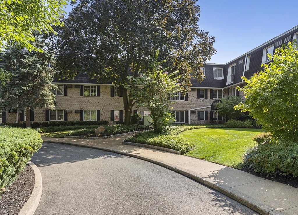 the front of a brick house with a driveway and a lawn