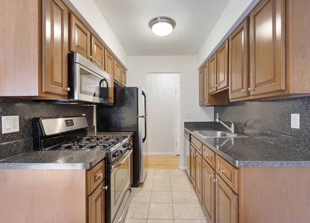 a kitchen with wood cabinets and granite counter tops and a stove and refrigerator
