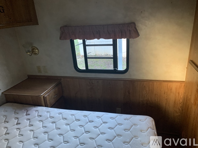 A bedroom with a bed, wooden dresser, and window.