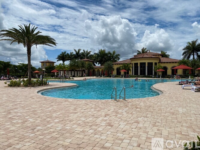 A large outdoor swimming pool surrounded by palm trees and a building in the background.