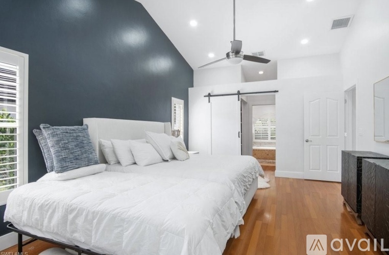 A bedroom with a large bed and a ceiling fan.