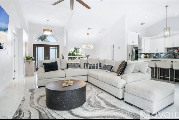 A modern living room with a large white sofa and a coffee table in the center.