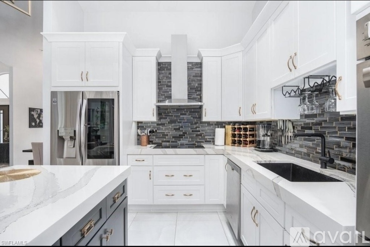 A modern kitchen with white cabinets and a marble countertop.