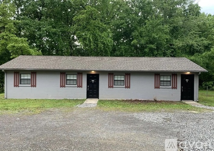 A small house with a black door and windows with red trim.