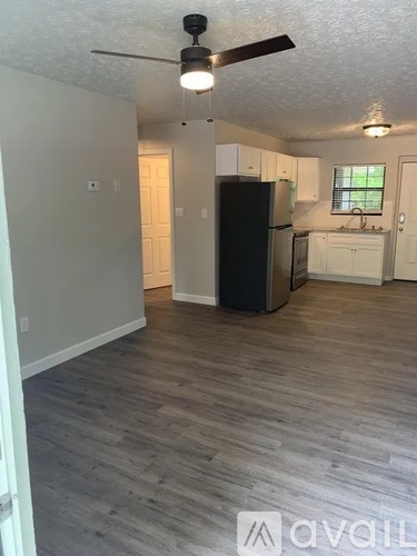 A kitchen with a black fridge and wooden floors.