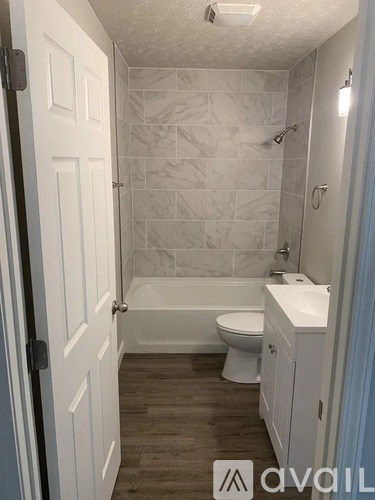 A bathroom with a white toilet, sink, and tiled walls.