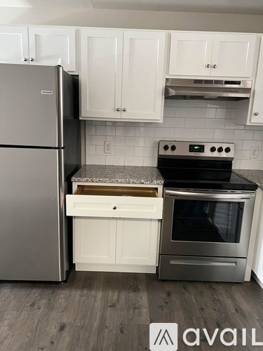 A kitchen with a refrigerator, oven, and cabinets.