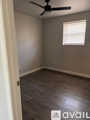 A room with a ceiling fan and a window with blinds.