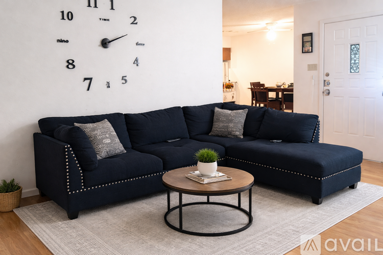 A living room with a large clock on the wall and a blue sofa.