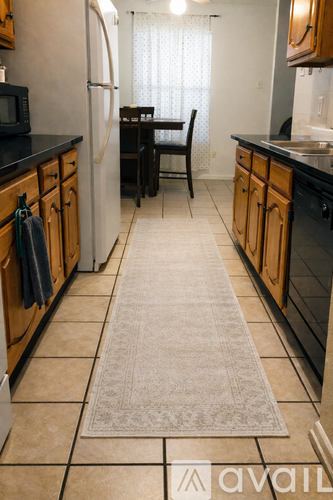 A kitchen with wooden cabinets and a rug on the floor.