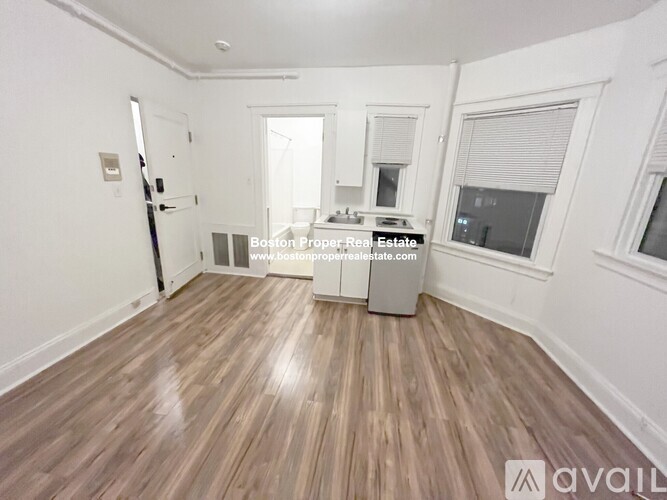 A spacious room with wooden flooring and white walls.
