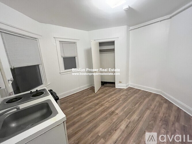 A kitchen area with a stove, sink, and wooden flooring.