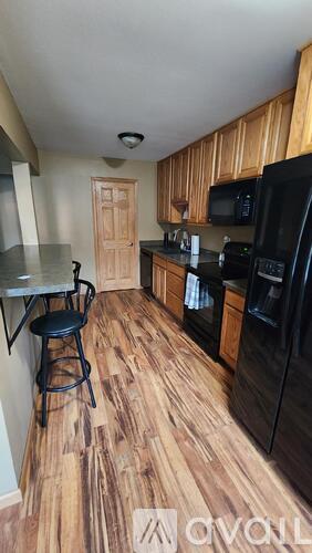 A kitchen with wood flooring and black appliances.