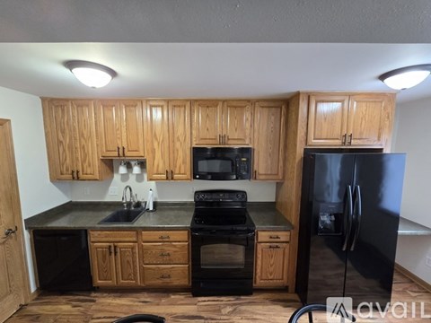 A kitchen with wooden cabinets and black appliances.