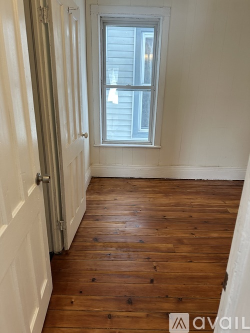 A hallway with wooden floors and white walls.