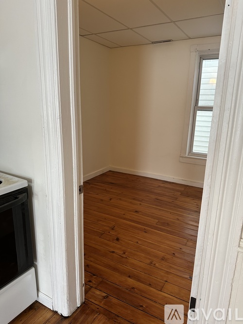 A room with wooden floors and a window with blinds.