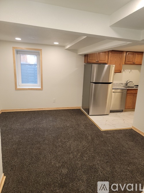 A kitchen area with a refrigerator, sink, and cabinets.