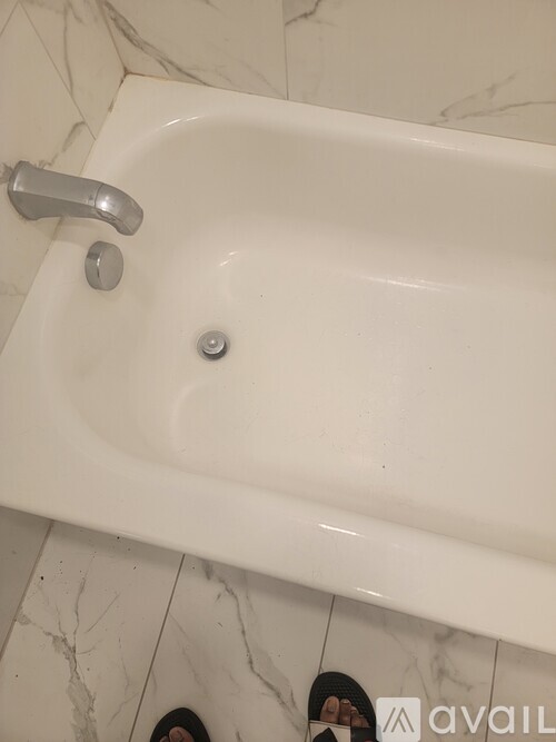A white bathroom sink with a silver faucet and a single screw in the middle.