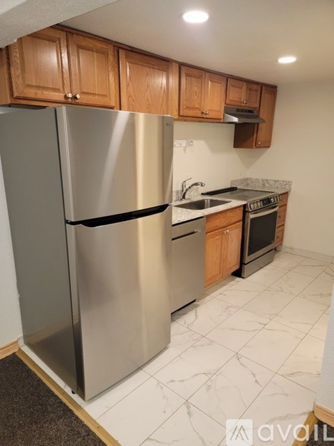 A kitchen with a stainless steel refrigerator and wooden cabinets.