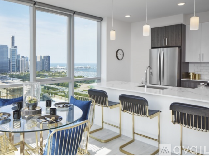 A modern kitchen with a glass table and bar stools with a view of the city.