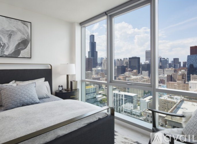 A bedroom with a large bed and a view of the city skyline.