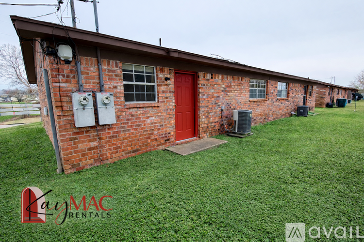 A brick house with a red door and a sign that says "Lay MAC Rentals".