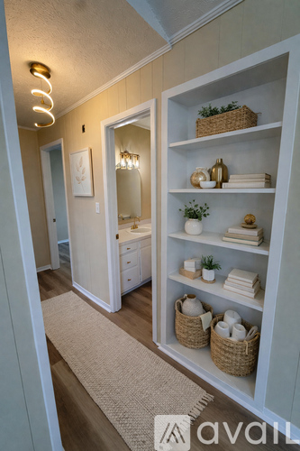 A kitchen with white cabinets and appliances, a window, and a wooden floor.