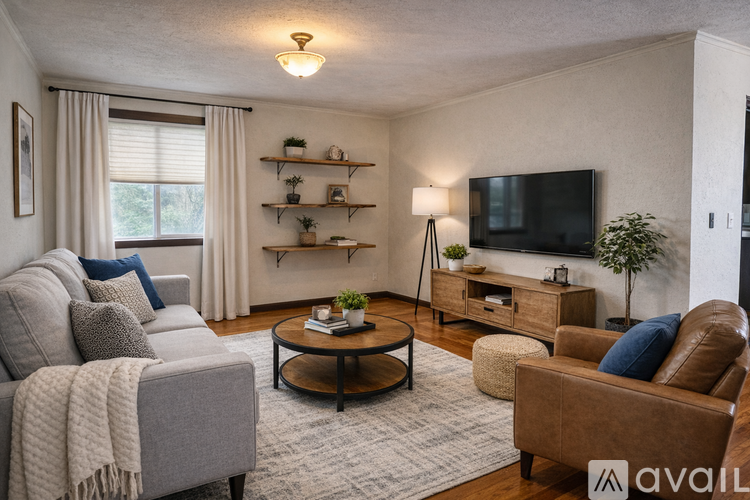 A living room with a grey couch, a brown leather chair, a wooden coffee table, and a flat screen TV mounted on the wall.