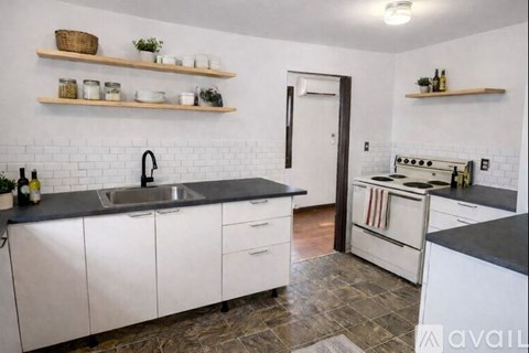 A kitchen with white cabinets and a black countertop.