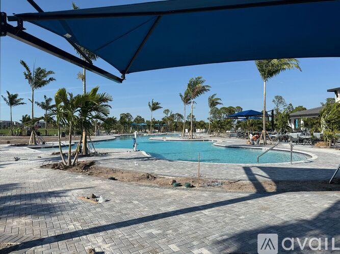 A pool surrounded by palm trees and a blue umbrella.