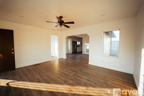 A spacious room with a ceiling fan and wooden flooring.