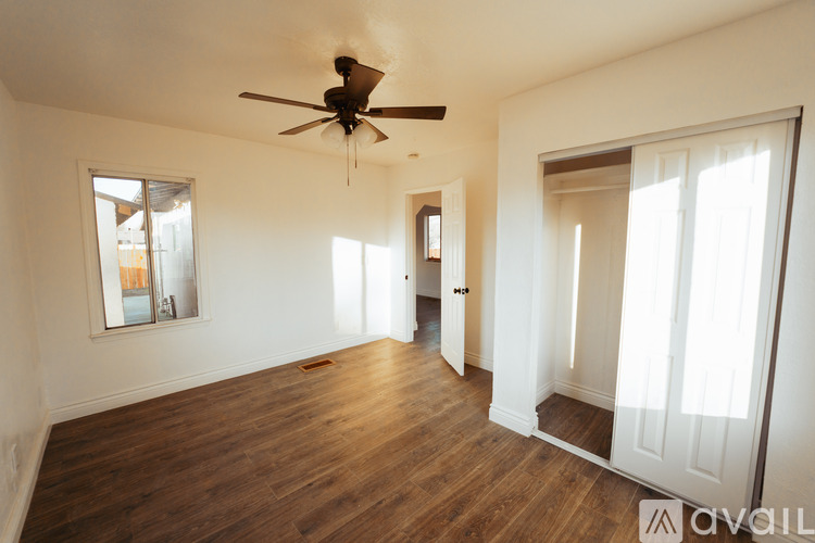 A room with a ceiling fan and wooden floors.