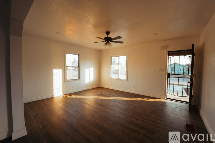 A spacious room with a ceiling fan and wooden flooring.