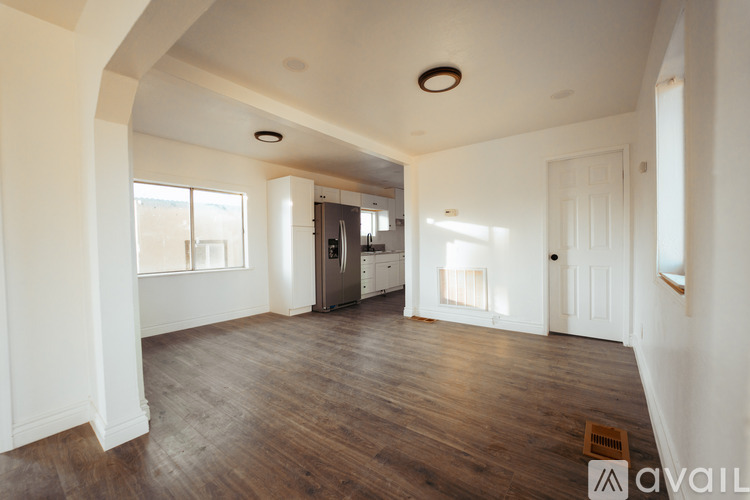 A spacious room with wooden floors and white walls.