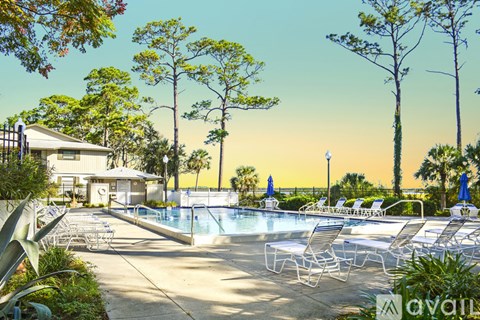 A pool surrounded by trees and chairs.
