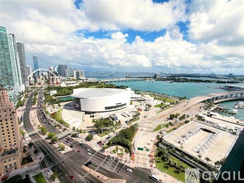 A cityscape with a large building in the center and a body of water in the background.