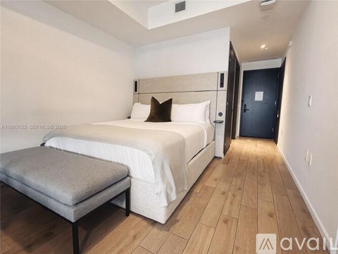 A bedroom with a large bed and a bench in front of it.