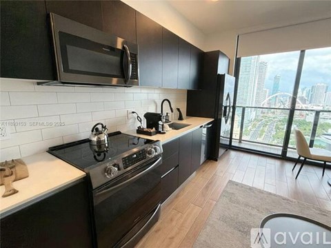 A modern kitchen with a stove, microwave, and a view of the city.