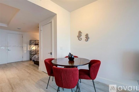 A dining room with a round table and red chairs.
