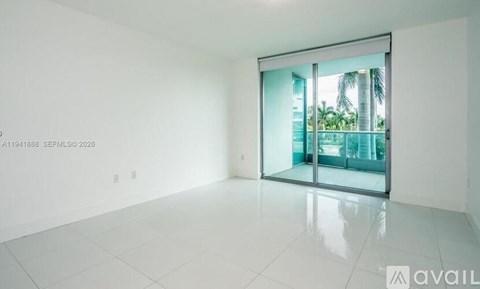 A spacious room with a sliding glass door leading to a balcony.