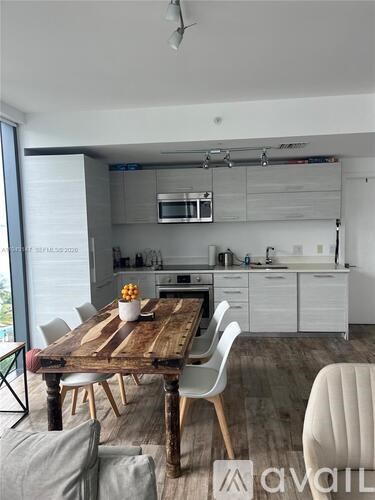 A modern kitchen with a wooden table and white chairs.