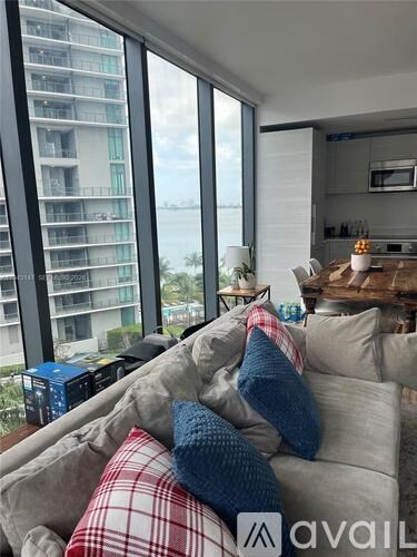 A living room with a couch and a large window overlooking a cityscape.
