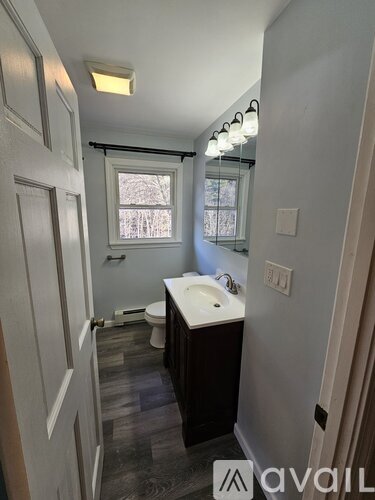 A bathroom with a toilet, sink and window.