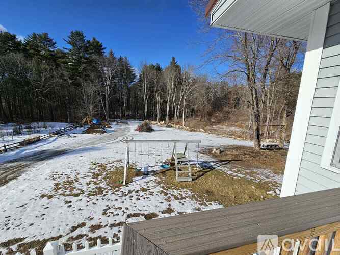 A snowy landscape with a wooden deck and trees in the background.