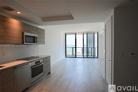 A modern kitchen with stainless steel appliances and a wooden accent wall.