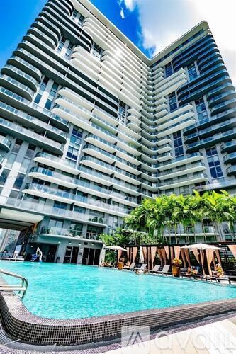 A tall building with a pool in front.