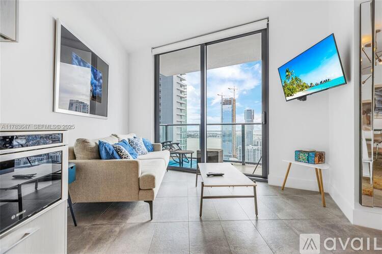 A living room with a couch, a chair, a table, and a television mounted on the wall.