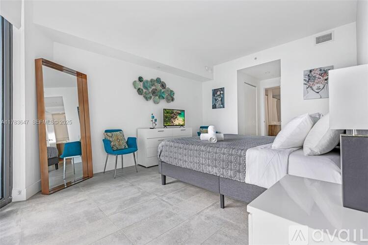 A bedroom with a bed, chair, and mirror.