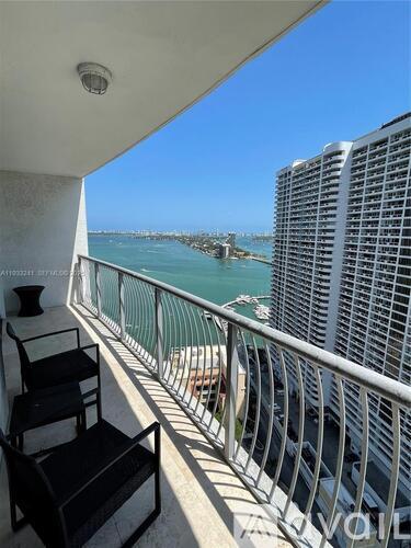 A balcony with a chair and a table overlooking the sea.